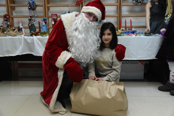 Santa Claus giving a package of gifts to Syrian-Armenian child through ONEArmenia's Santas Wanted! campaign.